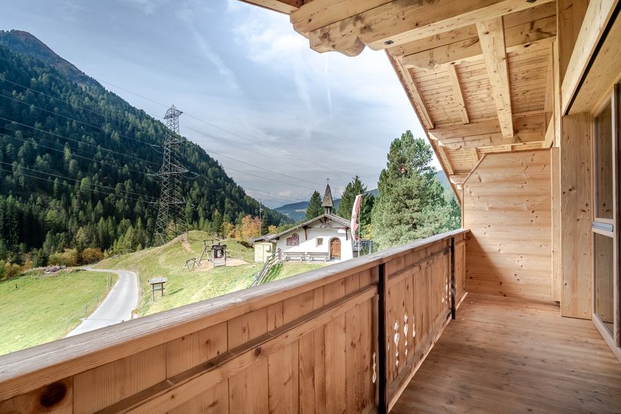 Holzbalkon mit Blick auf Kapelle und Berge am Almhof Mareil
