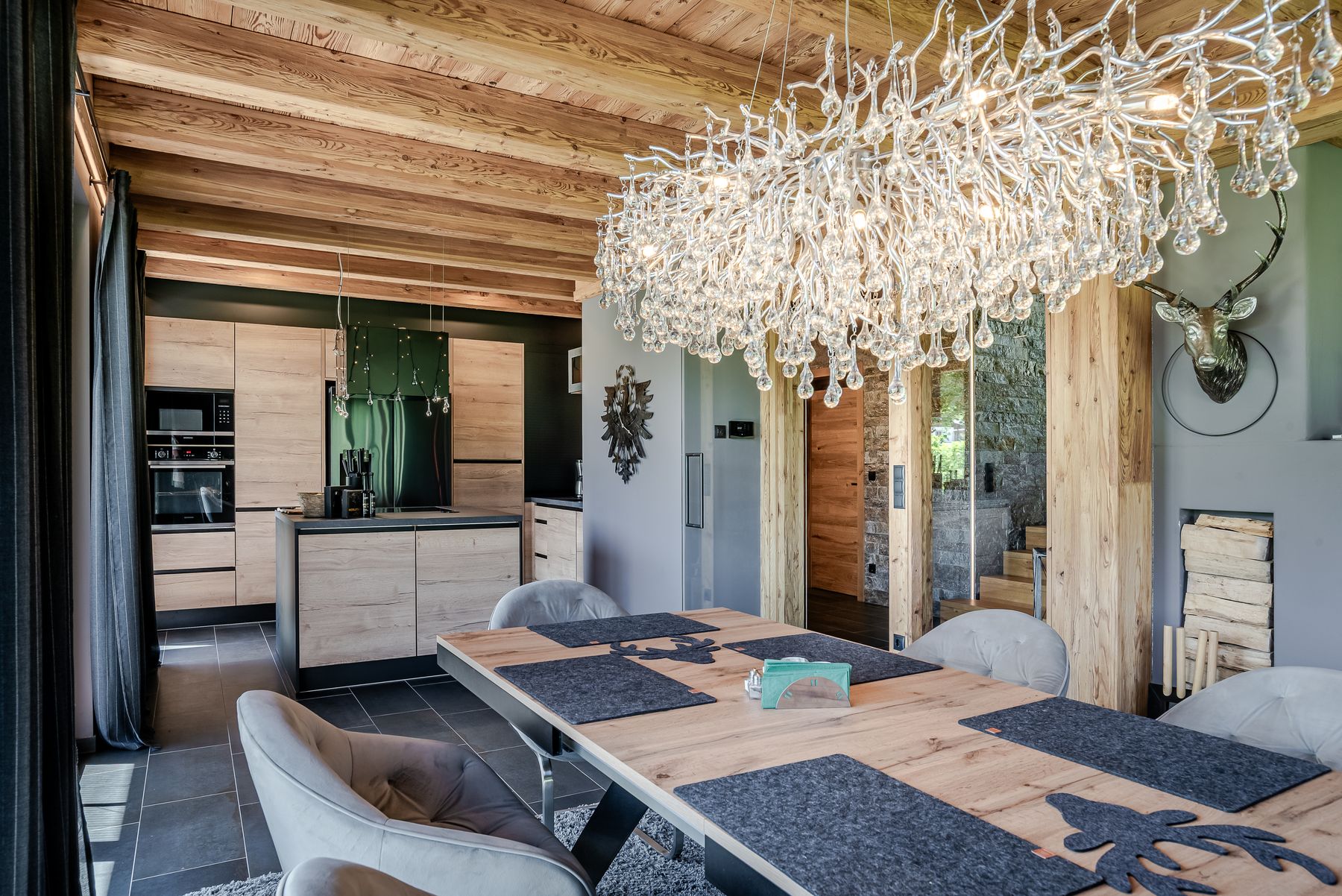 Essbereich mit Holztisch und großem Kristallleuchter unter Holzbalken